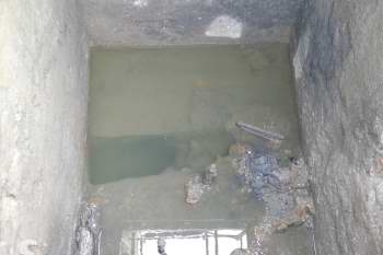 A view into a pit with some water filling the bottom