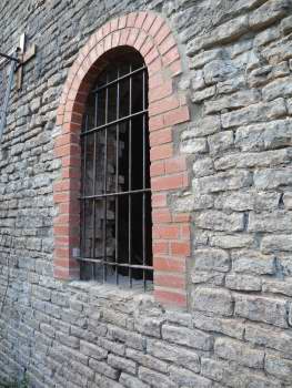 Black grille is set into a grey stone wall, surrounded by red bricks 