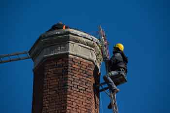 Mason working on top of chimney